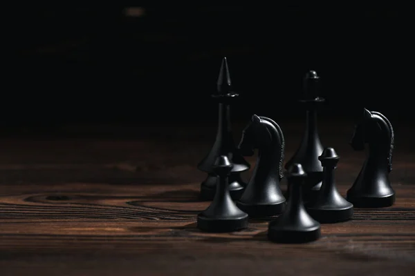Chess figures on wooden surface isolated on black — Stock Photo