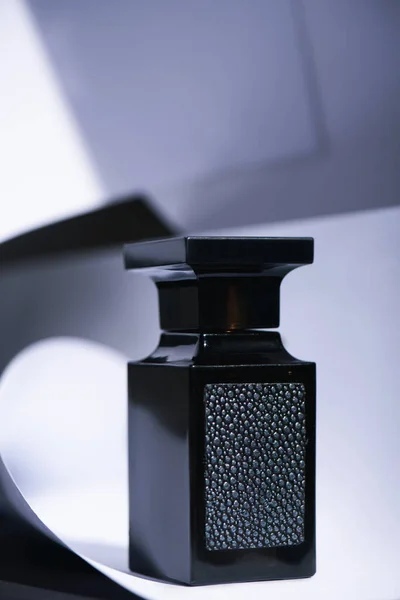 Foco selectivo de botella negra con perfume de lujo en blanco - foto de stock