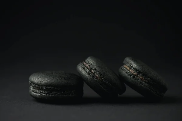 Dark and tasty macarons on black with copy space — Stock Photo