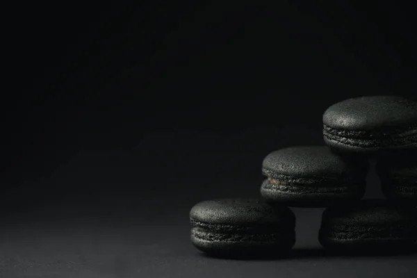 Macarons scuri e dolci su nero con spazio di copia — Foto stock