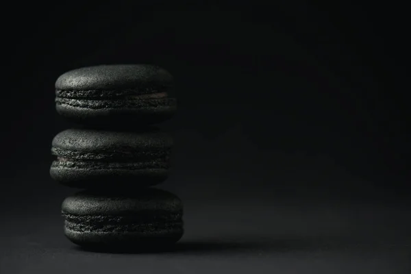 Delicious and dark macarons on black with copy space — Stock Photo