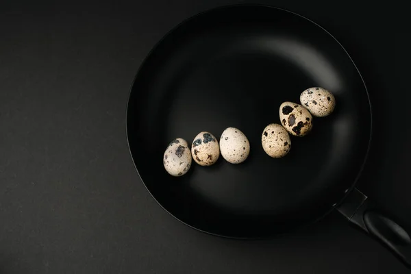 Top view of quail eggs on frying pan isolated on black — Stock Photo