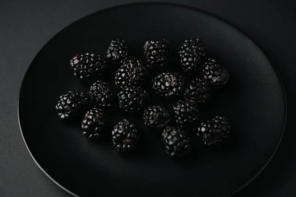 Teller von oben mit organischen und schmackhaften Brombeeren auf schwarz — Stockfoto