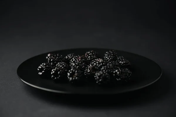 Plate with organic and tasty blackberries on black — Stock Photo