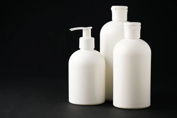 White bottles with cosmetics on black with copy space — Stock Photo