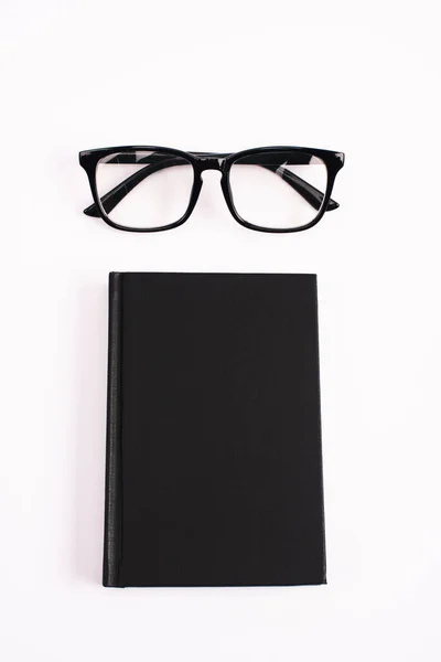 Vue du dessus des lunettes et carnet noir isolé sur blanc — Photo de stock