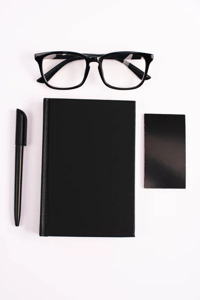 Vue du dessus des lunettes, bloc-notes, stylo et carte blanche isolé sur blanc — Photo de stock
