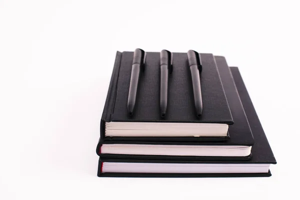Ручки на черных копировальных книгах изолированы на белом с копировальным пространством — стоковое фото