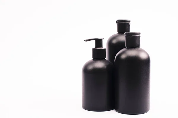 Black bottles with body lotion isolated on white — Stock Photo