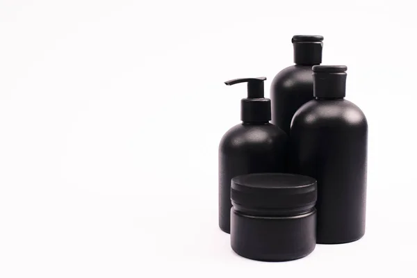 Black container near bottles with body lotion isolated on white — Stock Photo