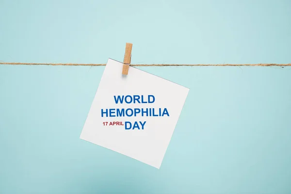 Card with world hemophilia day lettering on rope with pin isolated on blue — Stock Photo