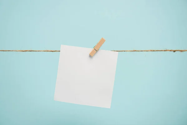 Carta vuota su corda con perno di legno isolato su blu — Foto stock