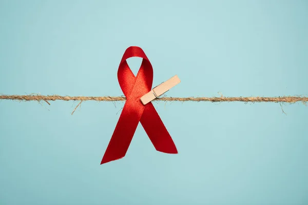 Pin with aids awareness red ribbon on rope isolated on blue — Stock Photo