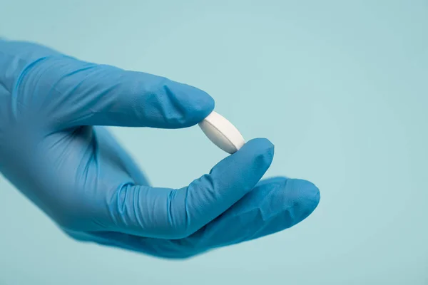 Cropped view of doctor in latex glove holding pill isolated on blue — Stock Photo