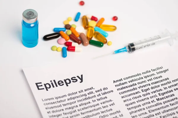 Papel con letras de epilepsia cerca del frasco, jeringa y pastillas sobre fondo blanco - foto de stock