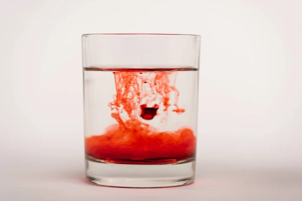 Drops of blood in glass with water on white surface — Stock Photo