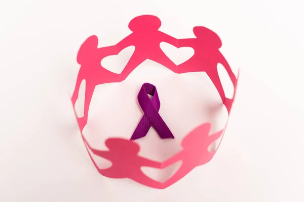 High angle view of purple ribbon and paper people figures on white background — Stock Photo