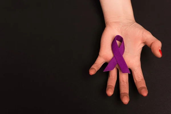 Top view of purple ribbon on woman hand isolated on black — Stock Photo