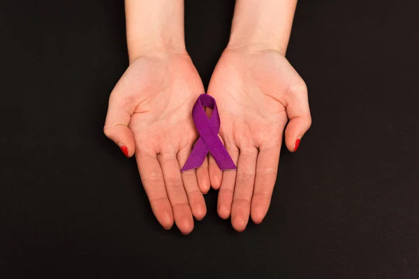 Top view of purple ribbon on hands of woman isolated on black — Stock Photo