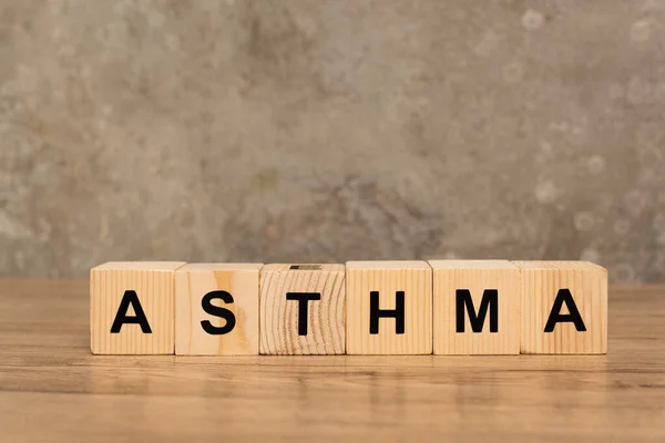 Wooden cubes with asthma lettering on wooden table on grey background — Stock Photo