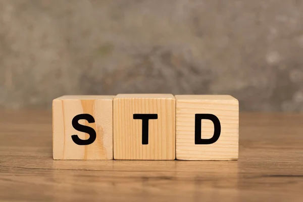 Blocs en bois avec lettres std sur table en bois sur fond gris — Photo de stock