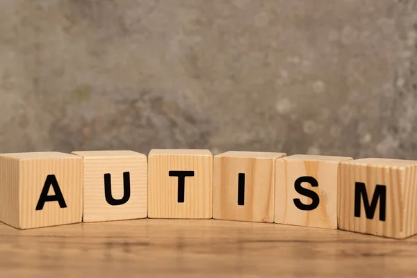 Cubes with autism lettering on wooden table on grey background — Stock Photo