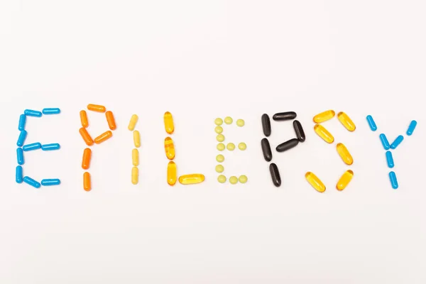 Vista superior de letras epilepsia de píldoras de colores aislados en blanco - foto de stock