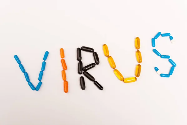 Top view of virus lettering from pills on white background — Stock Photo