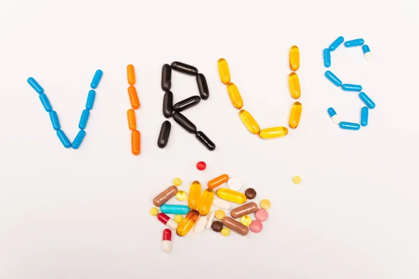 Vista dall'alto di virus lettering e mucchio di pillole su sfondo bianco — Foto stock