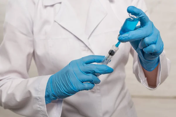 Vista recortada del médico recogiendo la vacuna en jeringa sobre fondo blanco - foto de stock