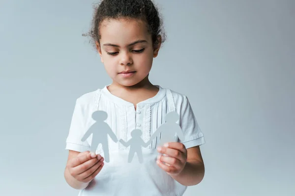 Niño afroamericano sosteniendo familia de papel aislado en gris, concepto de adopción - foto de stock