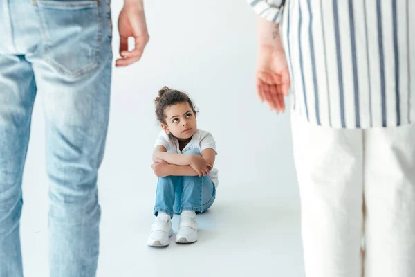 Selektiver Fokus eines afrikanisch-amerikanischen Kindes, das in der Nähe von Pflegeeltern auf Weiß sitzt — Stockfoto