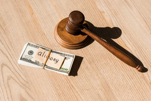 Wooden gavel near dollar banknotes and paper with alimony lettering on table — Stock Photo