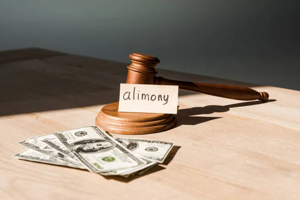 Gavel near dollar banknotes and paper with alimony lettering on table — Stock Photo