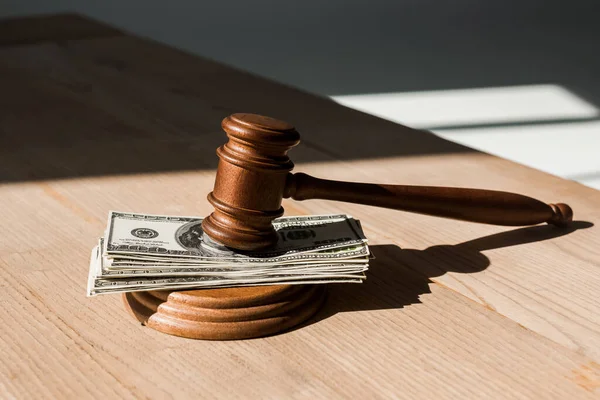 Wooden table with gavel on dollar banknotes — Stock Photo