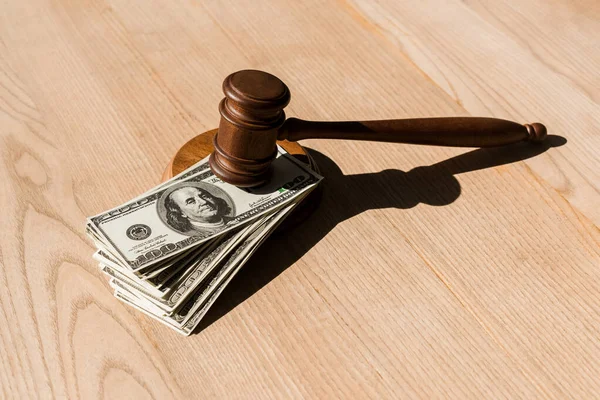 Wooden gavel on dollar banknotes and textured table — Stock Photo