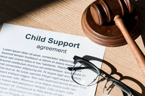 Wooden gavel near document with child support agreement and glasses — Stock Photo