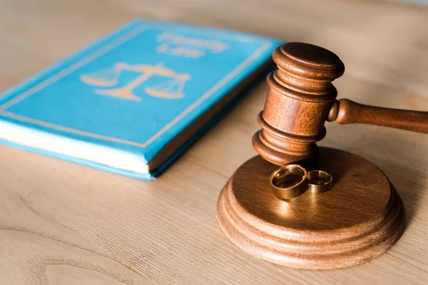 Selective focus of gavel near engagement rings and book on desk — Stock Photo
