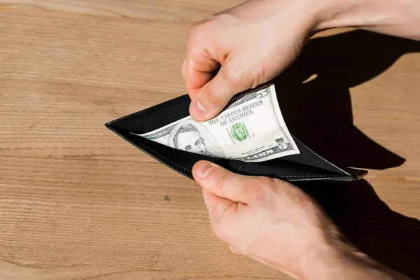 Обрезанный вид человека, держащего бумажник с долларовой купюрой — стоковое фото