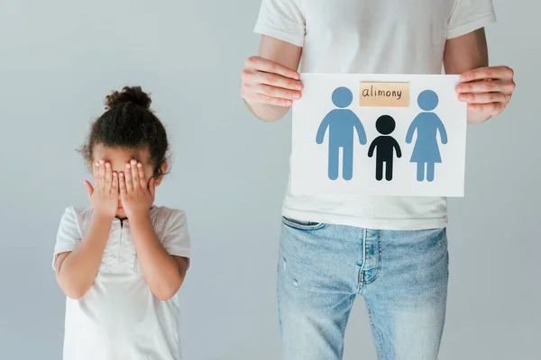 Father holding paper with drawn family and alimony lettering near upset african american daughter isolated on white — Stock Photo