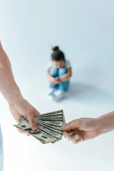 Selective focus of man giving alimony to woman near adopted child on white — Stock Photo