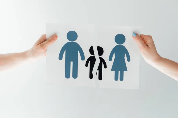 Vista recortada del hombre y la mujer sosteniendo papel rasgado con la familia separada en blanco - foto de stock