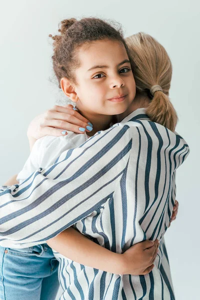 Vista posteriore della madre affidataria abbracciando carino ragazzo africano americano isolato su bianco — Foto stock