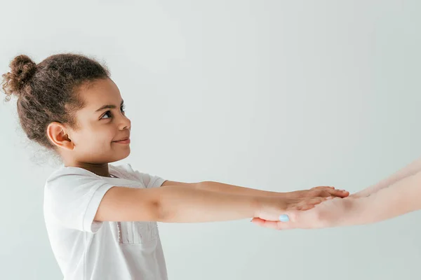 Madre cogida de la mano con niño afroamericano feliz y adoptado aislado en blanco - foto de stock