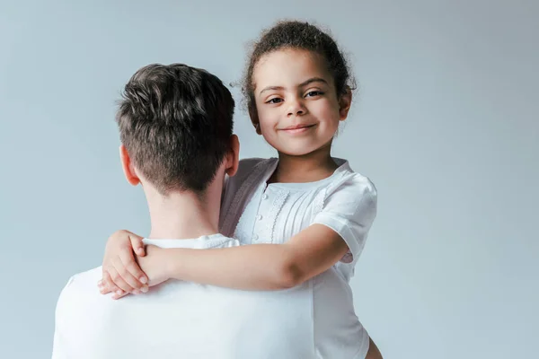 Rückseite der Ziehvater umarmt glücklich adoptierte afrikanisch-amerikanische Tochter isoliert auf weiß — Stockfoto