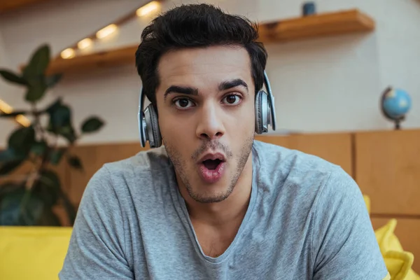 Hombre sorprendido en los auriculares mirando a la cámara - foto de stock