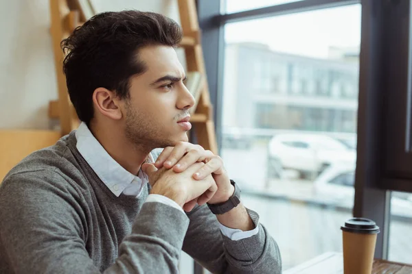 Thoughtful businessman with clenched hands near paper cup of coffee at table in office — Stock Photo