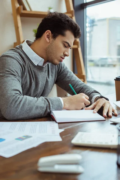 Selektiver Fokus des Geschäftsmannes, der in Notizbuch am Tisch im Büro schreibt — Stockfoto