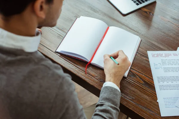 Ausgeschnittene Ansicht des Geschäftsmannes, der in Notizbuch am Tisch im Büro schreibt — Stockfoto