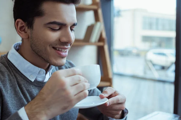 Uomo d'affari che sorride e tiene il piattino con una tazza di caffè — Foto stock